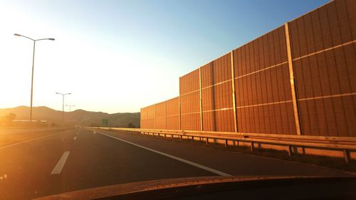 Noise barrier by road against sky seen through car windshield