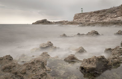 Scenic view of rocks in sea against sky