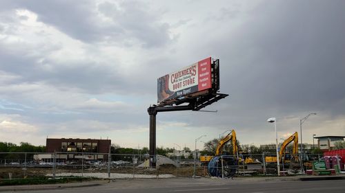 Information sign on road against sky in city