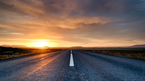 Road passing through landscape during sunset