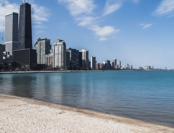 City at waterfront against cloudy sky