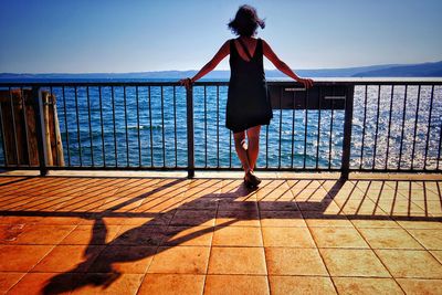 Rear view of woman standing on promenade against clear sky