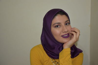 Portrait of smiling young woman against wall