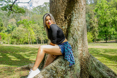 Young woman sitting on tree trunk