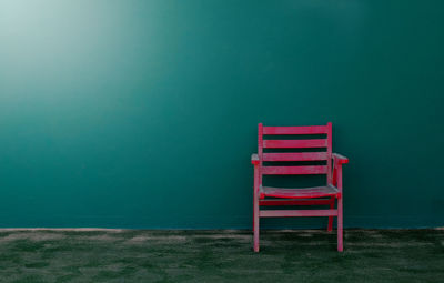 Red chair against green wall on tennis court 