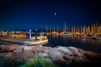 Sailboats moored at harbor against clear sky at night