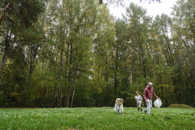 Father with son and daughter collecting garbage from grass