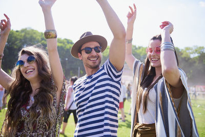 Smiling man and women dancing on grass against sky