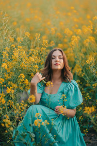 Portrait of young woman standing amidst yellow flowering plants