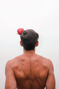 Rear view of shirtless man standing against white background