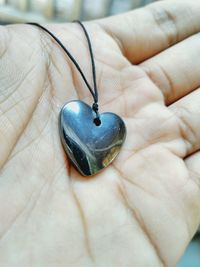 Close-up of hand holding heart shape locket