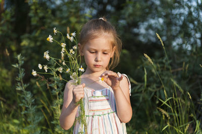 Cute girl looking away while standing on field