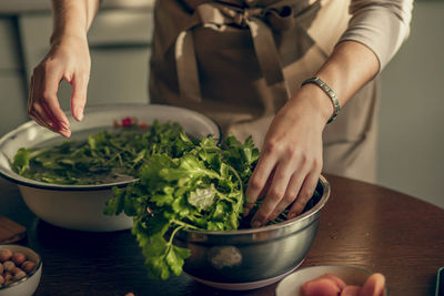 Preparing bowl of fresh greens, emphasizing farm-to-table connection, beauty of organic ingredients