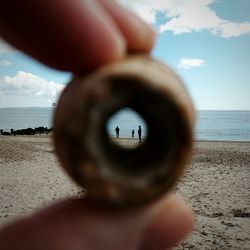 People standing on sea shore seen through hole