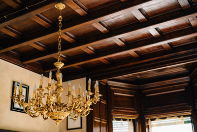 Low angle view of illuminated chandelier hanging on ceiling in building