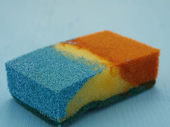Close up view to the sponge splitted by two colors - blue and orange on the blue background. 