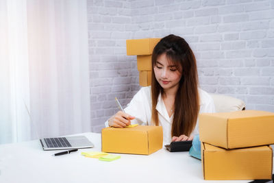 Young woman using mobile phone while sitting on table