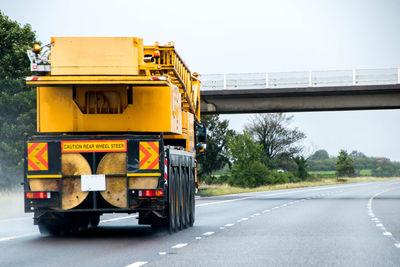 Yellow bridge by road against sky in city