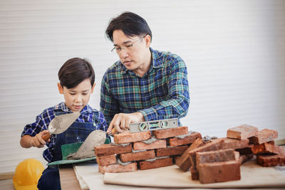 Father teaching son to make brick wall at workshop