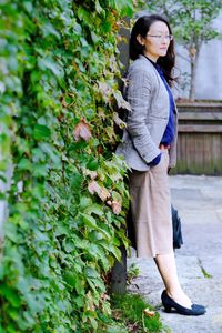 Woman in suit standing against plants