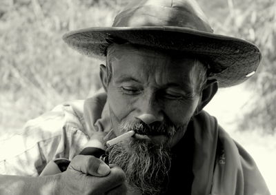 Close-up of mature man lighting cigarette while sitting outdoors