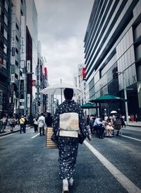 Rear view of people walking on city street