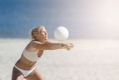 Midsection of woman with ball on beach