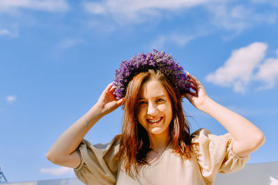 Portrait of young woman standing against sky