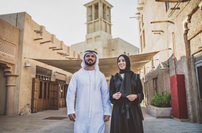 Smiling couple talking while walking on street in town