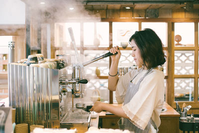 Side view of woman holding food in kitchen