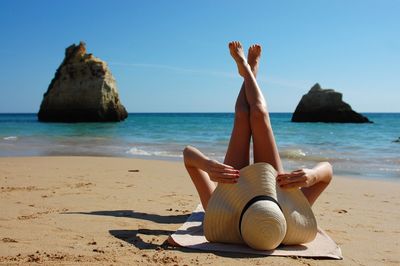 Woman sunbathing at beach against sky