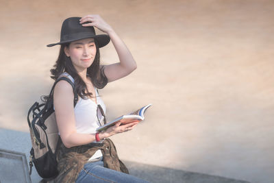 Young woman using mobile phone while sitting on camera