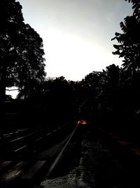 Railroad tracks amidst silhouette trees against sky