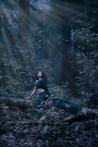 Woman sitting on rock in forest