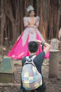 Rear view of man photographing woman in costume