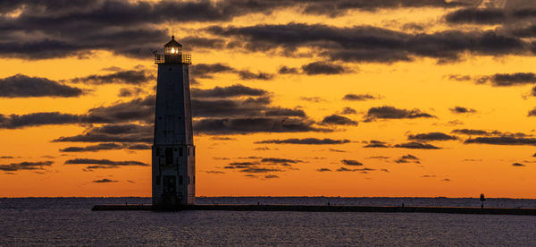 Glowing lighthouse under a vibrant sunset in the bay