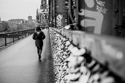 Rear view of men walking on footbridge in city