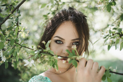 Portrait of beautiful young woman holding plants at park