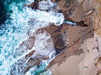 Aerial view of sea waves flowing on shore at beach