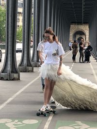 Woman standing on skateboard with people in background