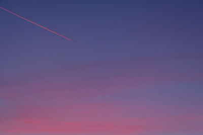 Aeroplane with condensation trail in dawn blue sky
