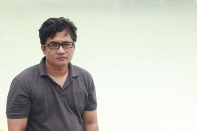 Portrait of young man standing against wall