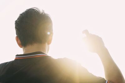 Rear view of man against sky on sunny day