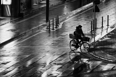 Man riding bicycle on wet street