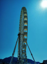 Low angle view of ferris wheel against clear blue sky