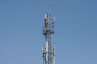 Low angle view of communications tower against clear blue sky