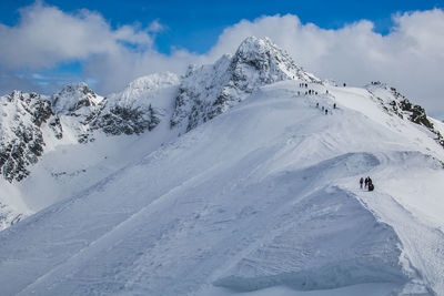 People skiing on snowcapped mountain against sky