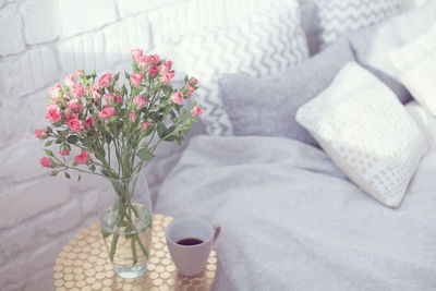 Flower vase and coffee on table by bed at home