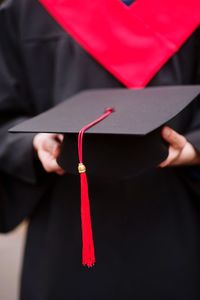 Midsection of male university student holding mortarboard