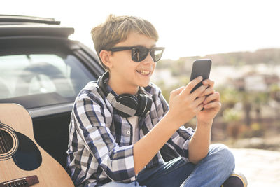 Smiling boy using mobile phone while sitting in car